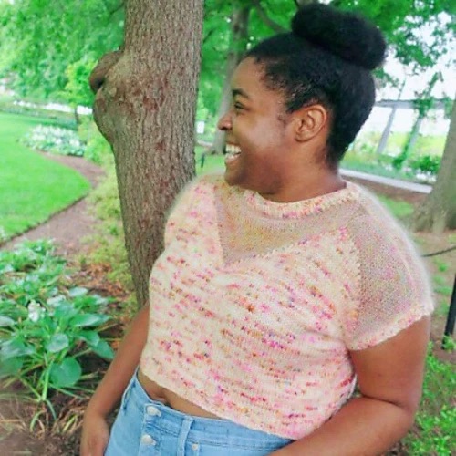 Smiling person wearing a pink and white knitted tee shirt with a sheer upper bodice