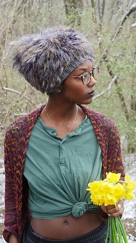 Person wearing a dark grey faux fur hat and holding a bunch of daffodils