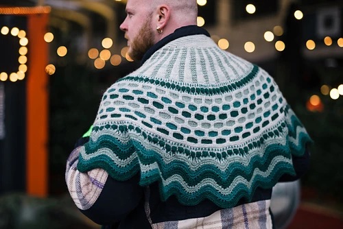 Person wearing a color work shawl in shades of green, grey, and white