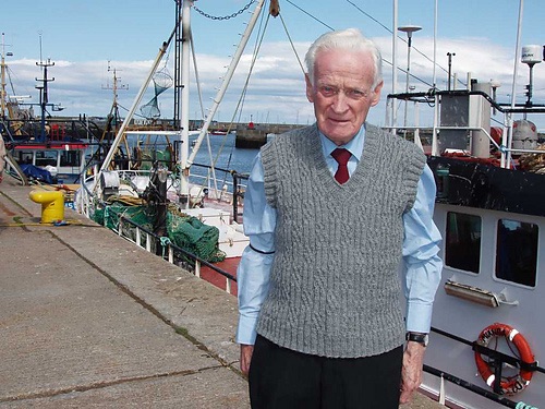 Person wearing a grey cabled knit vest 