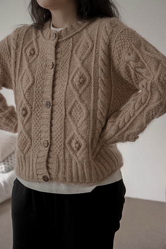 Person wearing a tan cabled cardigan