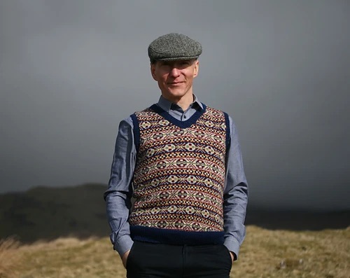 Person wearing a fair isle knitted vest and a nice cap